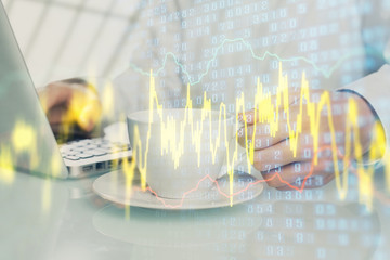 Double exposure of graph with man typing on computer in office on background. Concept of hard work.