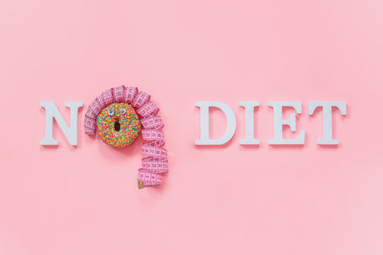 Text No diet and abstract funny face of woman from donut with eyes and hair from centimeter tape on plate on pink background. Concept International No Diet Day, 6 may Top view Flat lay Copy space