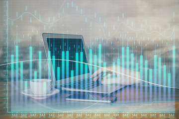 Double exposure of stock graph with businessman typing on computer in office on background. Concept of hard work.