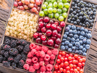 Colorful berries in wooden box on the table. Top view.