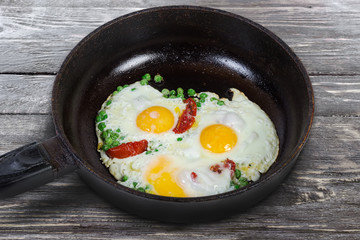 Eggs fried with green pea and tomatoes in frying pan