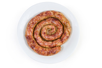 Top view of baked spiral homemade pork sausage on dish