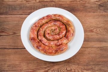 Baked homemade pork sausage curtailed by spiral on white dish