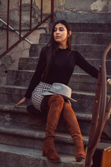 stylish girl model posing sitting on the steps of the building