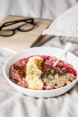 Oatmeal with berries, peanut butter, banana and chia in a white bowl.