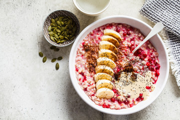 Oatmeal with berries, peanut butter, banana and chia in a white bowl, top view, copy space.