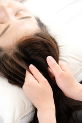 Fototapeta premium 頭皮マッサージを受ける女性と施術者の手元