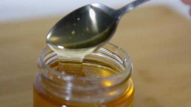 spoon is lowered into a jar of fragrant sweet honey and vypaskivaetsya from it. Honey drips from a spoon