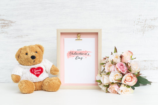 Mockup Picture frame and cute bear with Bouquet of pink roses on grunge white wood. Valentines Day Background concept with copy space. Mock up with photo frame for your picture or text