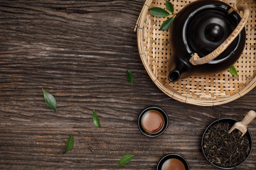 Obraz na płótnie Canvas Cup of hot tea with teapot, green tea leaves and dried herbs top view on the wooden table empty space, Organic product from the nature for healthy with traditional style