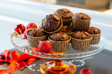 Chocolate cupcakes and red ornaments on a glass plate