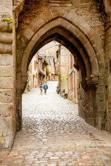 Old gates Porte du Jerzual in city wall and cobblestone Rue du Jerzual street in Dinan, Brittany, France © Natalia Bratslavsky