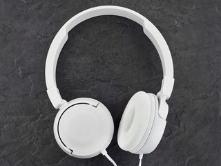 Modern white headphones on a stone background.