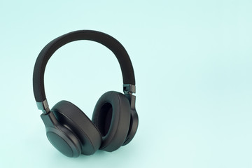 Modern wireless black headphones on a light blue background.