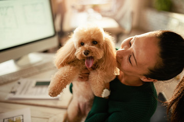 Happy Asian freelancer and her dog in the office.