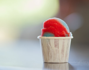 Sweet homemade rainbow italian shaved ice dessert in a paper cup