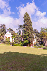 view from a sunny lawn to beautiful arbors among the lush southern vegetation in the city park of...