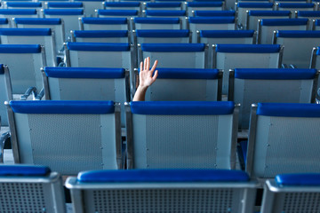 Naklejka premium Row of seats and a human hand in help gesture in airport hall