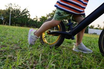 cute boy playing balance bike on grass field of playground