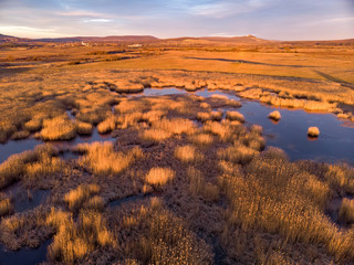 Aerial winter landscape over frozen pond in sunset light