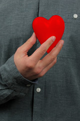 guy holds a red heart model in his hand in his hand, as a symbol of a declaration of love, concept of a declaration of love, marriage proposal, Valentine's Day, close-up