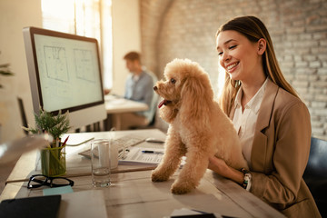 Happy businesswoman enjoying with her dog while working in the office.