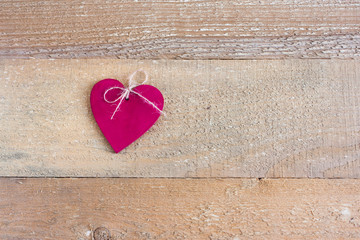 Red wooden heart on a background of unpainted and untreated boards. Valentine's day composition, selective focus.