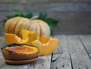 Cooking pumpkins. Home cooking, natural food for vegetarians. Traditional autumn pumpkin dishes. Grilled grilled pumpkin with spices on a background of raw whole pumpkin on a wooden background.