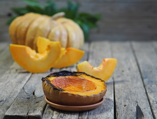 Cooking pumpkins. Home cooking, natural food for vegetarians. Traditional autumn pumpkin dishes. Grilled grilled pumpkin with spices on a background of raw whole pumpkin on a wooden background.