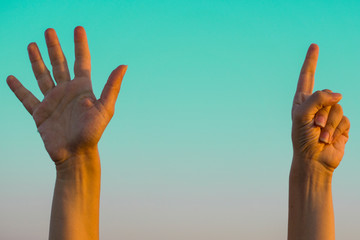 Hands doing / showing number six gesture symbol on blue summer sky nature background. Gesturing number 6. Number six in sign language. Sixth and counting down six concept. Six fingers up. Space for ad