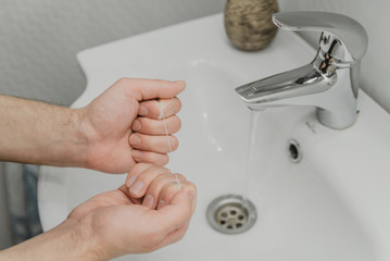 Flossing your teeth. a man holds a dental floss in his hands while standing in the bathroom. dental...