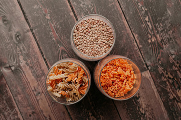 the option of smart food storage in the kitchen, three glass jars for storing raw pasta and groats on a dark wooden table