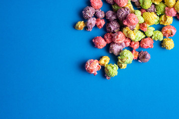 Multicolored fruit flavored popcorn on blue background. Candy coated popcorn.