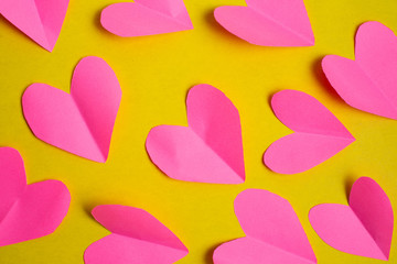 Red paper hearts on yellow background. Valentine's Day concept.
