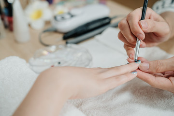 unrecognized asian female manicurist treating young woman client at beauty salon. Manicure stage of...