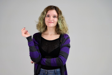 Fototapeta premium Portrait of a pretty student girl with beautiful curly hair. Concept horizontal photo of a young woman with emotions in a dark jacket standing in front of the camera on a white background.