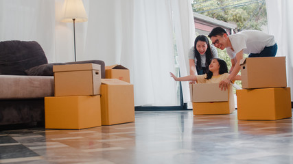 Happy Asian young family having fun laughing moving into new home. Japanese parents mother and...