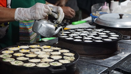 Traditional Thai desserts. The female vendor is dressing up on the mold. Kanom Krok in Thailand  - obrazy, fototapety, plakaty