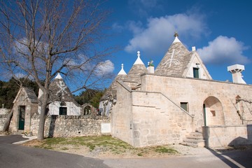 Group of beautiful Trulli with symbols, traditional old houses and old stone wall in Puglia, Italy, Europe