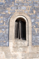 Ancient stone window of an old stone house in a countryside village in Puglia, Italy, Europe, vertical