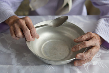 View from above.The hands of an old grandmother of 90 years are holding an empty aluminum bowl and...