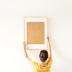 Woman hold blank photo frame with empty copy space on white background. Minimal photographer artist...