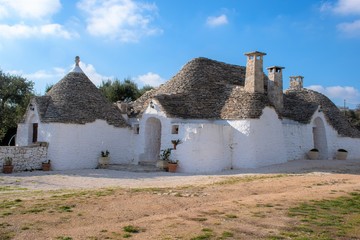 Group of Trulli with garden, traditional old houses and old stone wall in Puglia, Italy, Europe