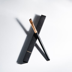 Light background with highlights for the site. A tool for a makeup artist. Makeup brush. Black plastic eyebrow brush.