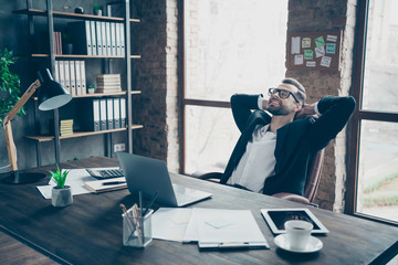 Photo of handsome business brunet guy holding hands behind head smiling positively enjoy little working break wear specs black blazer shirt suit sitting chair office indoors