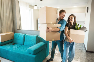 Fototapeta na wymiar young couple man and woman looking happy standing with boxes in their hands in new appartment unpacking boxes