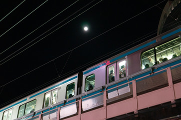 東京、帰宅ラッシュ時の混雑した電車と月