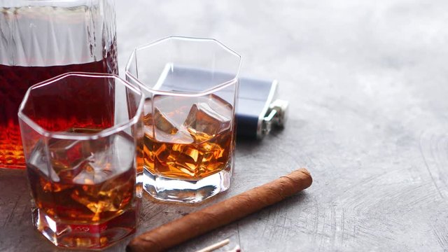 Two glasses of old whiskey with cuban cigar and carafe