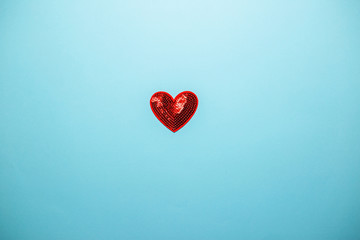 Small red heart of sequins with copy space. Saint Valentine's day card on blue background.