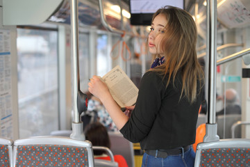 Beautiful young woman in tram reading book